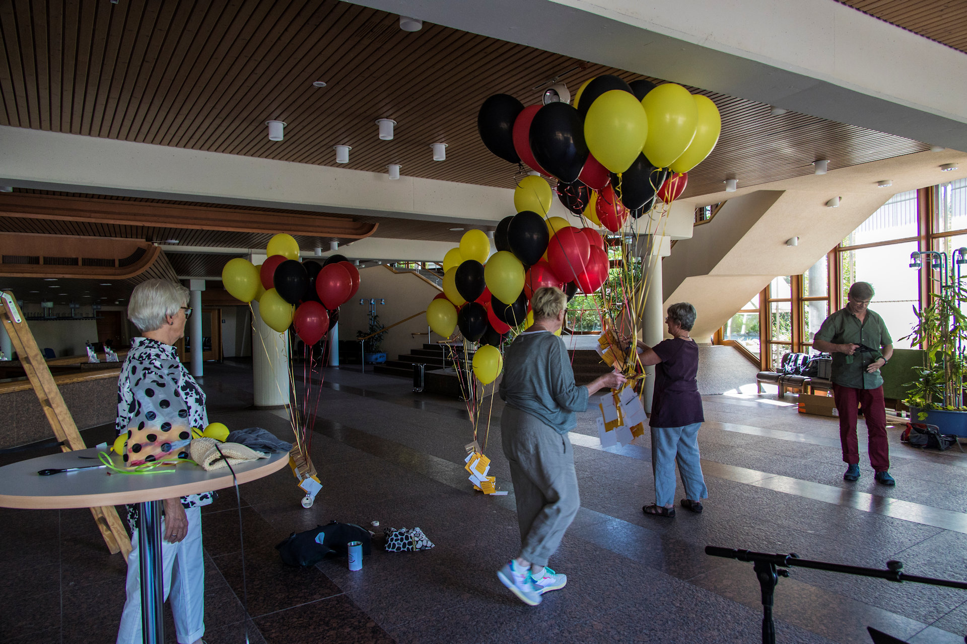 Menschen in einem schatigen Raum und Bündel von Luftballonen